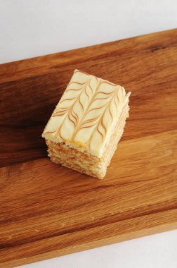 Slice of traditional Hungarian and Austrian Esterhazy cake on wooden board, close-up