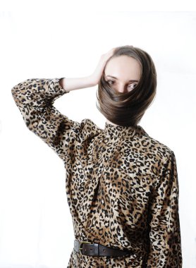 Yüzüne maske gibi dolanmış uzun saçlar. Moda saç modeli konsepti. Model bir leopar elbisesi giyiyor. Beyaz üzerine stüdyo fotoğrafı