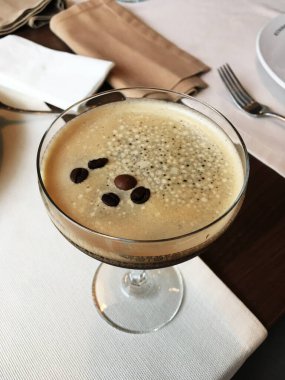 Kahve çekirdekli martini bardağında Espresso kahve kokteyli. Restoranda bir masanın üzerinde, yakın plan.