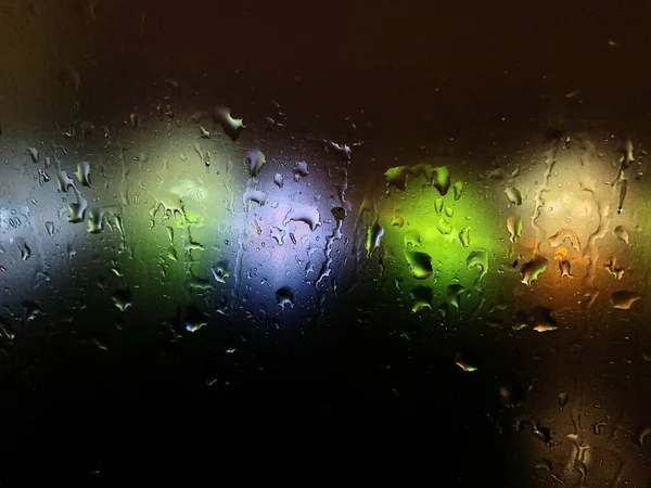 Kolorowe Światła Rozmyte Ciemnym Tle Przez Krople Oknie — Zdjęcie stockowe