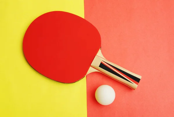 Red table tennis racket and ping pong ball on yellow red. Sport concept