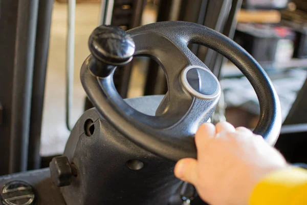 Hand rotates the steering wheel of the electric forklift, right, left. Turn and steer the driving machinery.