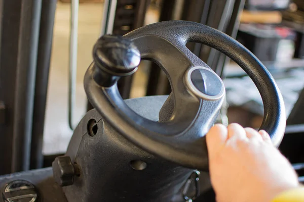 Hand rotates the steering wheel of the electric forklift, right, left. Turn and steer the driving machinery.