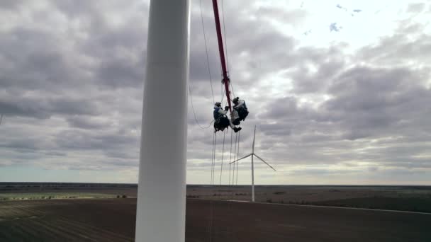 Stavitelé opravit větrem poháněné turbíny čepel pod zataženou oblohou — Stock video