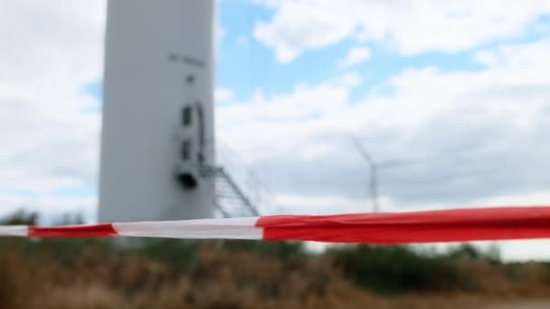 Nastro di segnalazione che segna i confini della zona di esclusione sullo sfondo della turbina eolica. — Video Stock