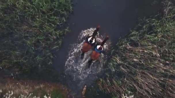 As mulheres montam cavalos castanhos em todo o jardim florescente e rio — Vídeo de Stock