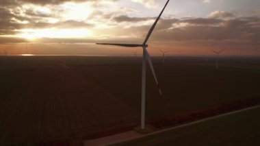 Wind turbines with big blades operate in field after sunset