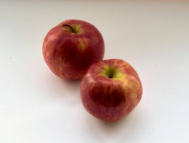 Beyaz bir zemin üzerinde doğal ışık altında olgun kırmızı elmalar.