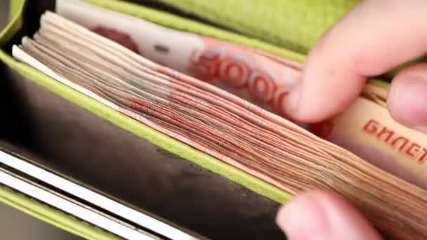 Handen tellen roebel bankbiljetten in een groene portemonnee close-up. Contant, vijfduizend biljetten. Financieel en zakelijk concept. Russisch geld — Stockvideo
