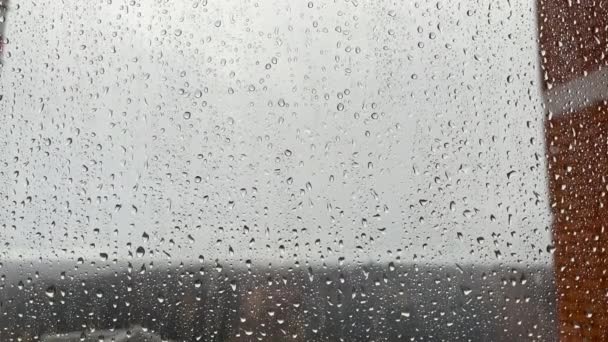 Pencerenin camındaki yağmur damlalarının dokusu bulutlu bir gökyüzünün arka planına yakın çekim, yavaşça aşağı akış, kötü hava, üzgün ruh hali, kopyalama alanı konsepti — Stok video