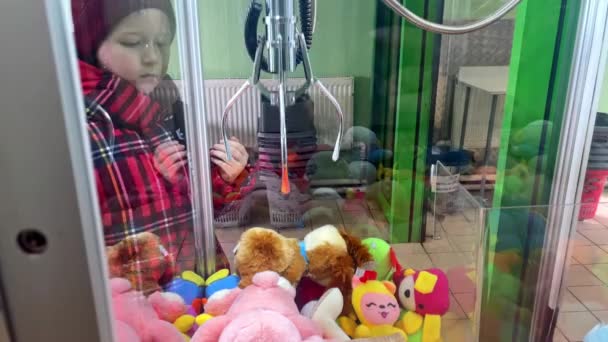 작은 코카서스 여자 애가 쇼핑몰에서 갖고 있는 부드러운 장난감으로 발톱 놀이를 하고 있습니다. 상을 타고, 손해를 보고, 생활 방식을 유지하려는 시도는 성공하지 못했다 — 비디오