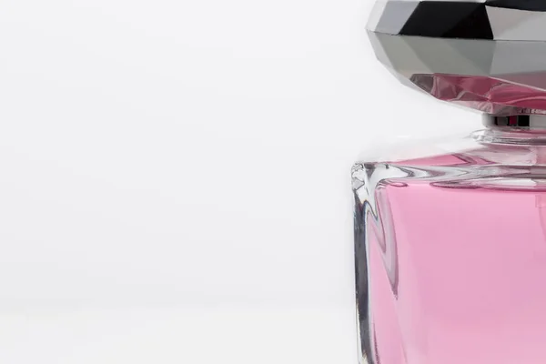 Άρωμα σε ένα γυάλινο μπουκάλι γκρο πλαν σε λευκό φόντο με μια θέση για κείμενο, περικοπεί φωτογραφία. Ροζ διαφανές αρωματικό υγρό γκρο πλαν. Ομορφιά θηλυκό λεπτή εορταστική έννοια — Φωτογραφία Αρχείου