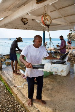 Deniz kıyısında çiğ balık temizleyen adamlar.