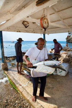 Deniz kıyısında çiğ balık temizleyen adamlar.