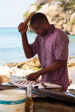 Deniz kıyısında çiğ balık temizleyen adam.