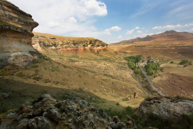 Kuru otlar, çalılar ve kayalarla panoramik dağlık arazi