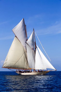 Schooner açık mavi gökyüzü ile denizde süzülüyor.