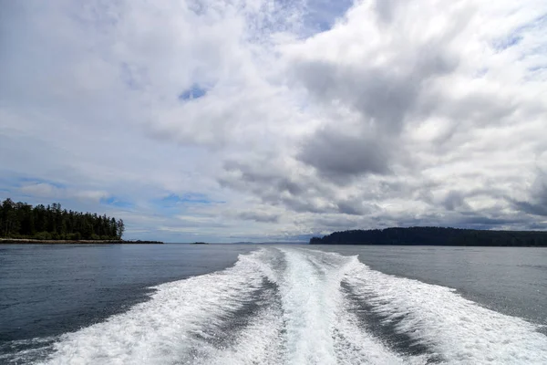 An outboard motor wake from a cruising powerboat on the sea in a seascape with the horizon over water on a cloudy day at Langara Island located in Haida Gwaii, British Columbia, Canada.