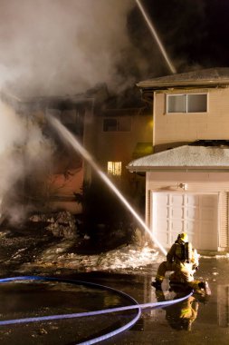 Squamish, British Columbia, Canada - December 12, 2016: Fireman extinguishing a house fire at night in a townhouse complex in Squamish, British Columbia, Canada.