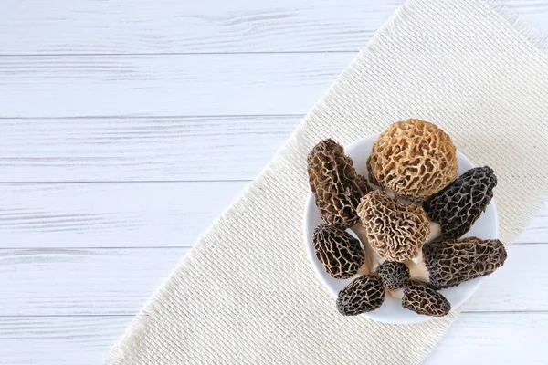 Several spring morel mushrooms lie in a white plate, on a cloth, on a table. — 스톡 사진