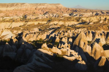 Kapadokya 'nın tipik jeolojik oluşumlarının şaşırtıcı hava manzarası. İnanılmaz şekilli kumtaşı kayaları. Ünlü turistik yer ve romantik seyahat yeri. Sonbahar gün batımı görünümü.