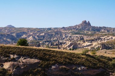 Kapadokya 'nın tipik jeolojik oluşumlarının güzel panoramik manzara fotoğrafı. İnanılmaz şekilli kumtaşı kayaları. Ufukta antik Uchisar. Ünlü turistik yer ve romantik seyahat merkezi..