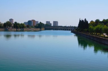 Adana 'nın manzaralı şehri. Seyhan Nehri üzerindeki yüksek binalar ve köprü. Mavi gökyüzü arkaplanı.
