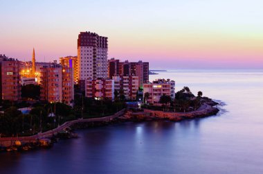 Tipik küçük Türk kasabasının resimli sabah manzarası. Türkiye 'nin Mersin kenti yakınlarındaki Akdeniz kıyısındaki yerleşim yeri. Binalar arasındaki caminin yüksek minaresi.