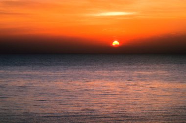 Güneş 'in diski deniz ufkundan yükseliyor. Sakin denizde parlak, güzel bir gün doğumu. Suyun üzerinde güneş diski. Türkiye 'nin Mersin kenti yakınlarındaki Akdeniz. Seyahat ve turizm kavramı. 