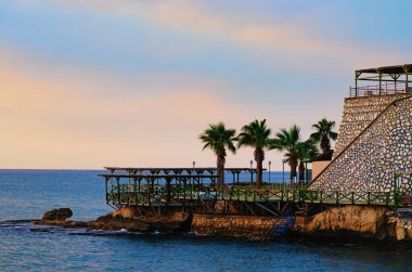 Türkiye 'de otel yakınlarında bir tatil köyü. Boş şezlonglar ve palmiye ağaçları olan toprak seti manzarası. Arka planda Akdeniz var. Seyahat ve turizm kavramı.