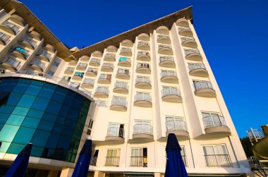 Morning view of facade hotel building with many windows and small balcones. Blue sky background. Travel and tourism concept.