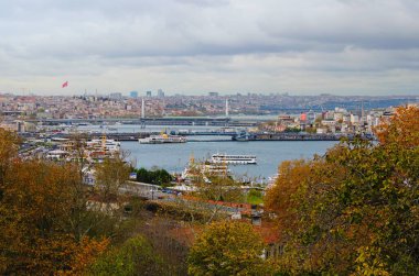 İstanbul, Türkiye-25 Ekim 2021: The Golden Horn, Galata Köprüsü 'nün birçok restoranı, Atatürk Köprüsü ve ufukta binaları bulunan pitoresk sonbahar manzarası. Ağaç kenarı.