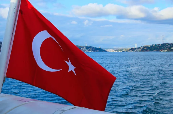 Türk Bayrağı rüzgârda. İstanbul ve Boğaz 'ın bulanık şehir manzarası (İstanbul Boğazı veya Boğazı). Beyaz hilal ve kırmızı arkaplanda bir yıldız.