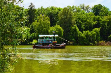 Uman, Ukrayna-19 Haziran 2021: Parkın üst göletindeki turistik geminin manzarası. Arka planda yeşil yapraklar var. Güneşli bir günde Sofievsky Bahçesi (Sofiyivsky Parkı). 