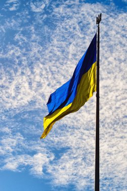 The Biggest National flag Ukraine against blue sky with fantastic soft clouds. Blue and yellow flag of Ukraine. Waving Ukrainian flag.  Portrait orientation.