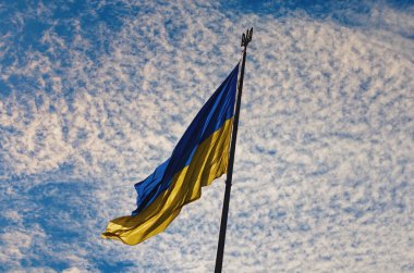The Biggest National flag Ukraine against blue sky with fantastic soft clouds. Blue and yellow flag of Ukraine. Waving Ukrainian flag. Landscape orientation.