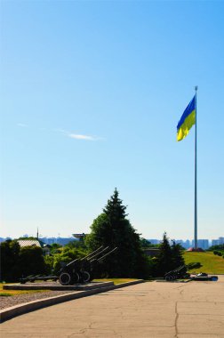 Kyiv, Ukraine-June 19,2022:National Museum of the History of Ukraine in the Second World War. Groups of vintage guns and old tank. National flag Ukraine in the background. Sunny morning sky.