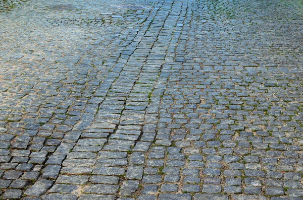Cobbled road as background. The gray paving stones close up. The texture of the old dark stone. Vintage, grunge. Road surface. Brick stone street road. Pavement abstract texture.