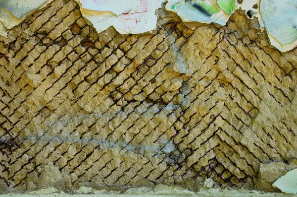 View of old clay surface.Abstract background, clay texture. Aged clay texture.The wall of abandoned house. Remnants of a metal mesh in clay wall. Old rural house clay wall fixed by wirecloth (Rabitz).