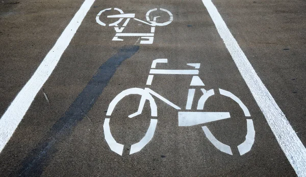 Bicycle road sign on the road. Two white bicycle symbols on an asphalt cycle path. An empty bicycle lane with markings and a bicycle signs. A place for safe rides and walks in the outdoors
