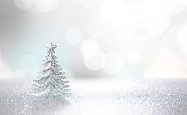 Winter christmas scenic background template. Silvery small Christmas tree on a blurred defocused background in pearl silver tones with copy space.