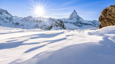İsviçre 'de Zermatt yakınlarındaki Matterhorn manzaralı Alp güneşli kış manzarası. Ön planda soğuk irtifa rüzgarı tarafından şekillendirilmiş donmuş kar tabakası..