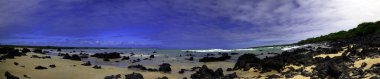 Güney Amerika 'daki Galapagos Adaları' ndaki plajda uzanan siyah volkanik kayaların panoraması.