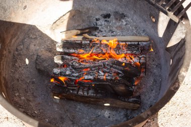 A view looking inside a bonfire. Flames burn through firewood.