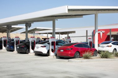 Kettleman City, California, ABD - 09-08-2021: Tesla araçlarının bir Tesla Supercharger istasyonundaki elektrik direklerine bağlanmış görüntüsü.