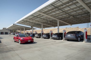 Kettleman City, California, ABD - 09-08-2021: Tesla Supercharger istasyonunun yanından geçen bir Tesla aracının görüntüsü.