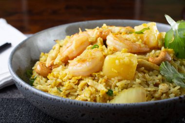 A view of a bowl of shrimp fried rice, in a restaurant or kitchen setting,