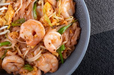 A top down view of a bowl of Pad Thai, in a restaurant or kitchen setting.