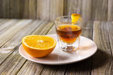 A view of a half orange next to a whiskey shot with a wedge, in a restaurant or kitchen setting.