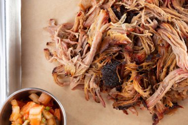 A top down view of a tray of barbecued pulled pork, in a restaurant or kitchen setting.